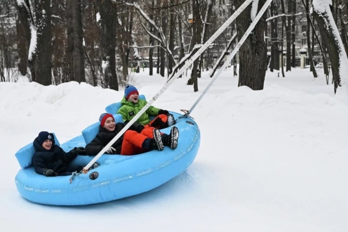    Дети катаются на бесплатном аттракционе электротюбинг в парке Северного речного вокзала в Москве.