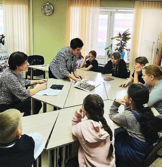 Березикова Екатерина Анатольевна показывает детям фотографии из альбома