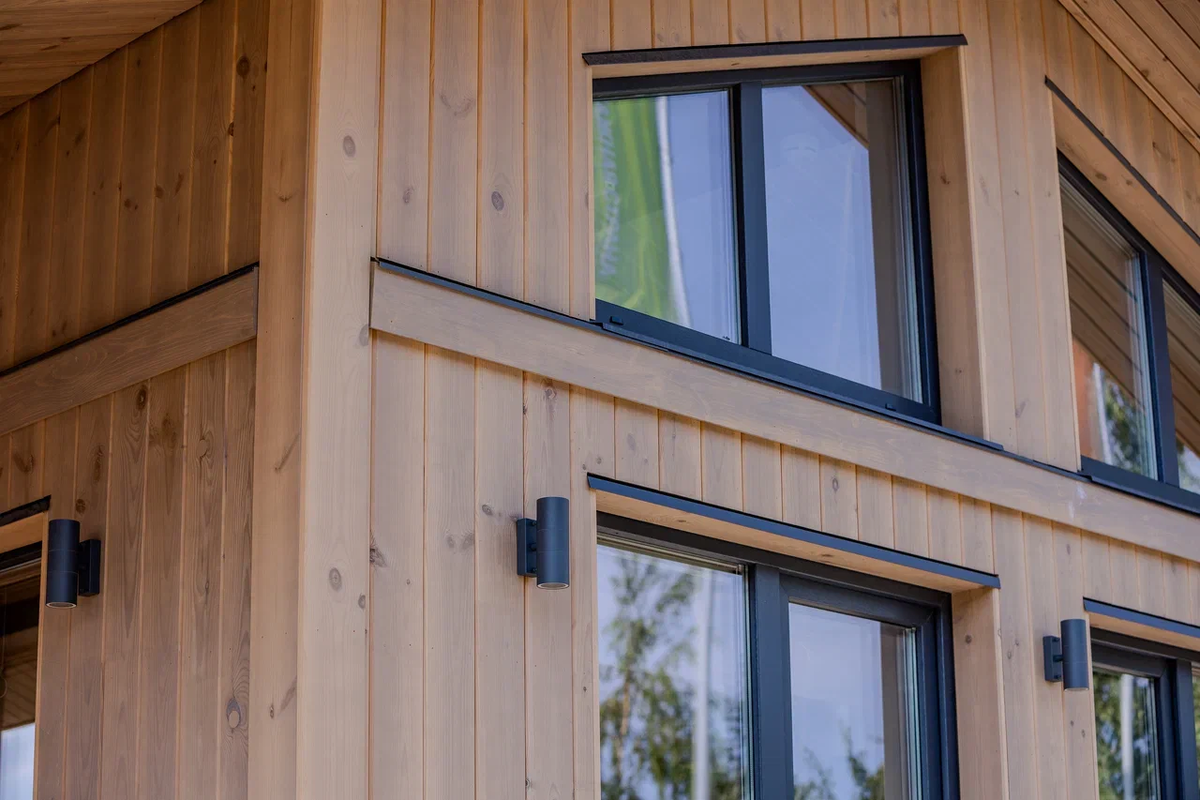 Открытие прошлого года — вертикальные деревянные облицовки. Еще недавно упорно имитировала дома из бруса и была горизонтальной, вертикальные — казались слишком смелыми и по большей части ассоциировались с хозпостройками, или стилистикой барнхаус, которая, также образец «амбарного стиля». В 2025 году фасады с вертикальной деревянной облицовкой стали трендом строительных выставок, и, пожалуй, обошли или вот-вот обойдут классическую имитацию бруса. По крайней мере, сейчас — они вполне мирно соседствуют.