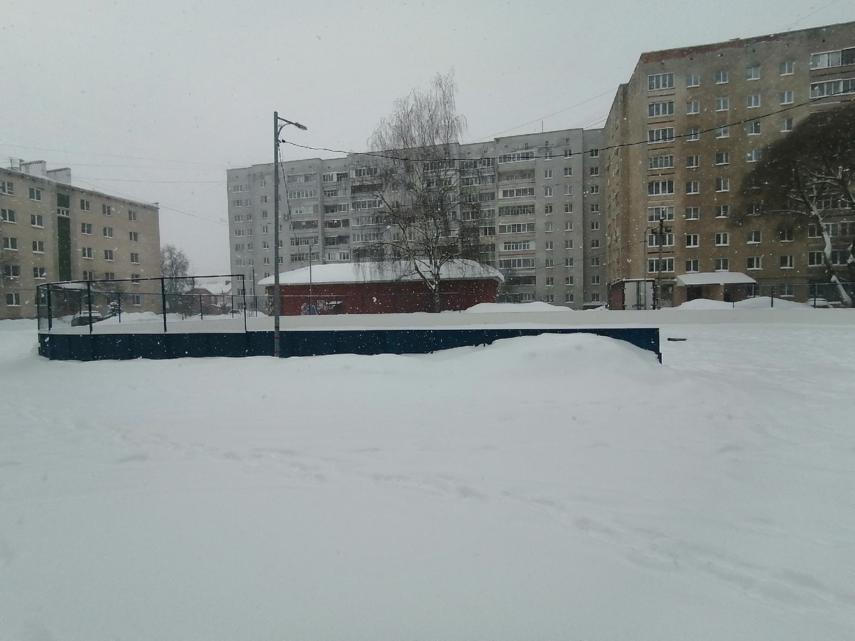 Вид на хокейную коробку во дворе домов. Буквально вчера заливали лед. А в момент фотографирования все засыпано. 