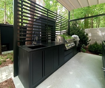 Современная уличная модульная кухня-барбекю с чёрной гранитной столешницей.