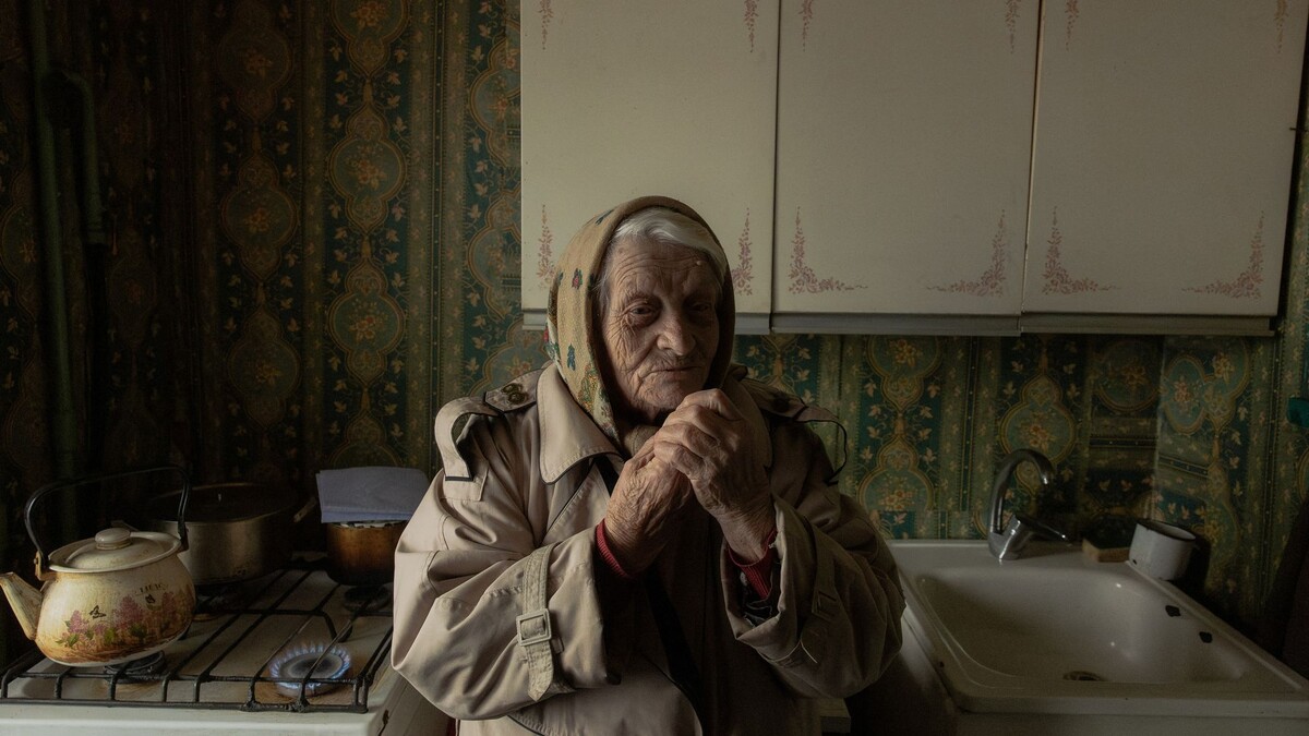 Евгения Ерёмина, 89-летняя пенсионерка, стоит на кухне и греется у газовой плиты в своей квартире в Киеве 26 января. Фото: Роман Пилипей / AFP via Getty