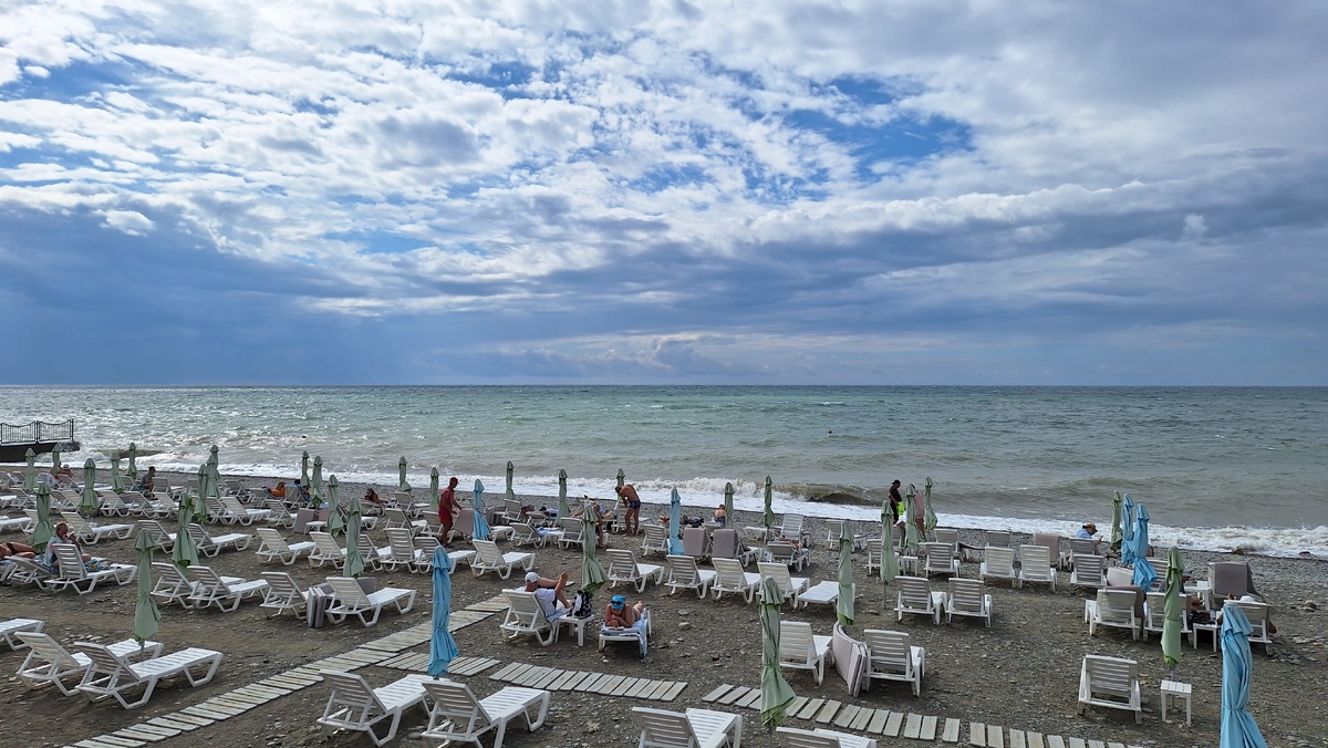 Почти пустой пляж. Люди загорают, но не купаются