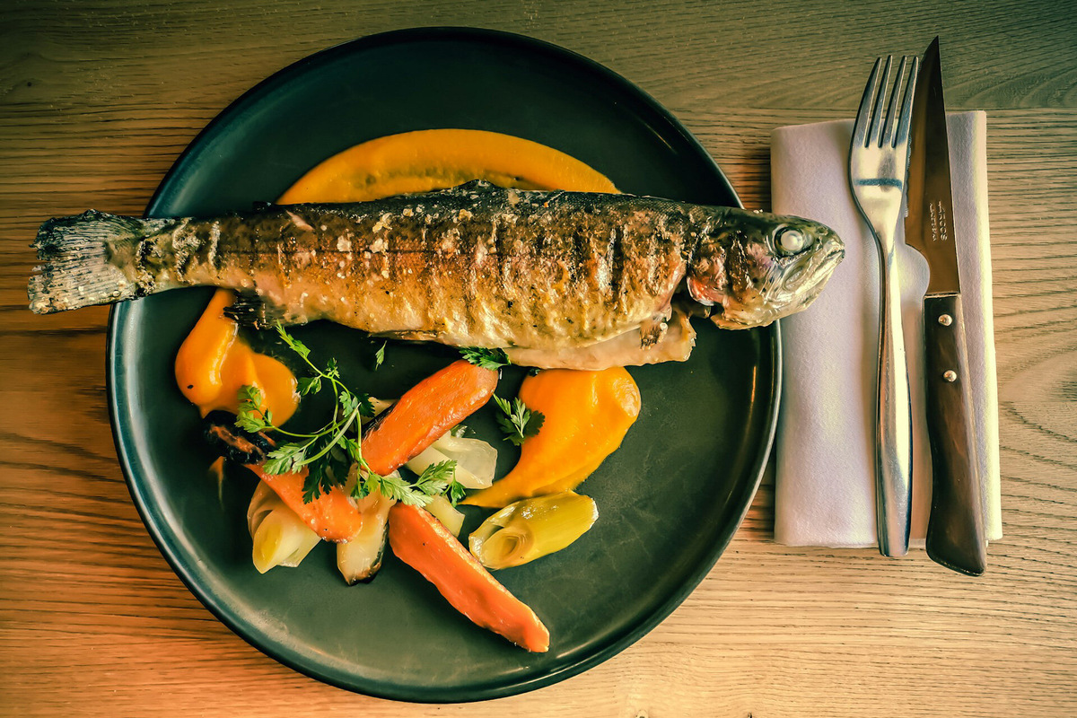 Вкус свежепойманной форели лучше всего раскрывается во время копчения или на гриле. За счёт большой жировой прослойки мясо получается нежное и сочное. Перед бронированием экскурсии или размещением уточните, есть ли мангал. Фото: Jametlene Reskp / Unsplash