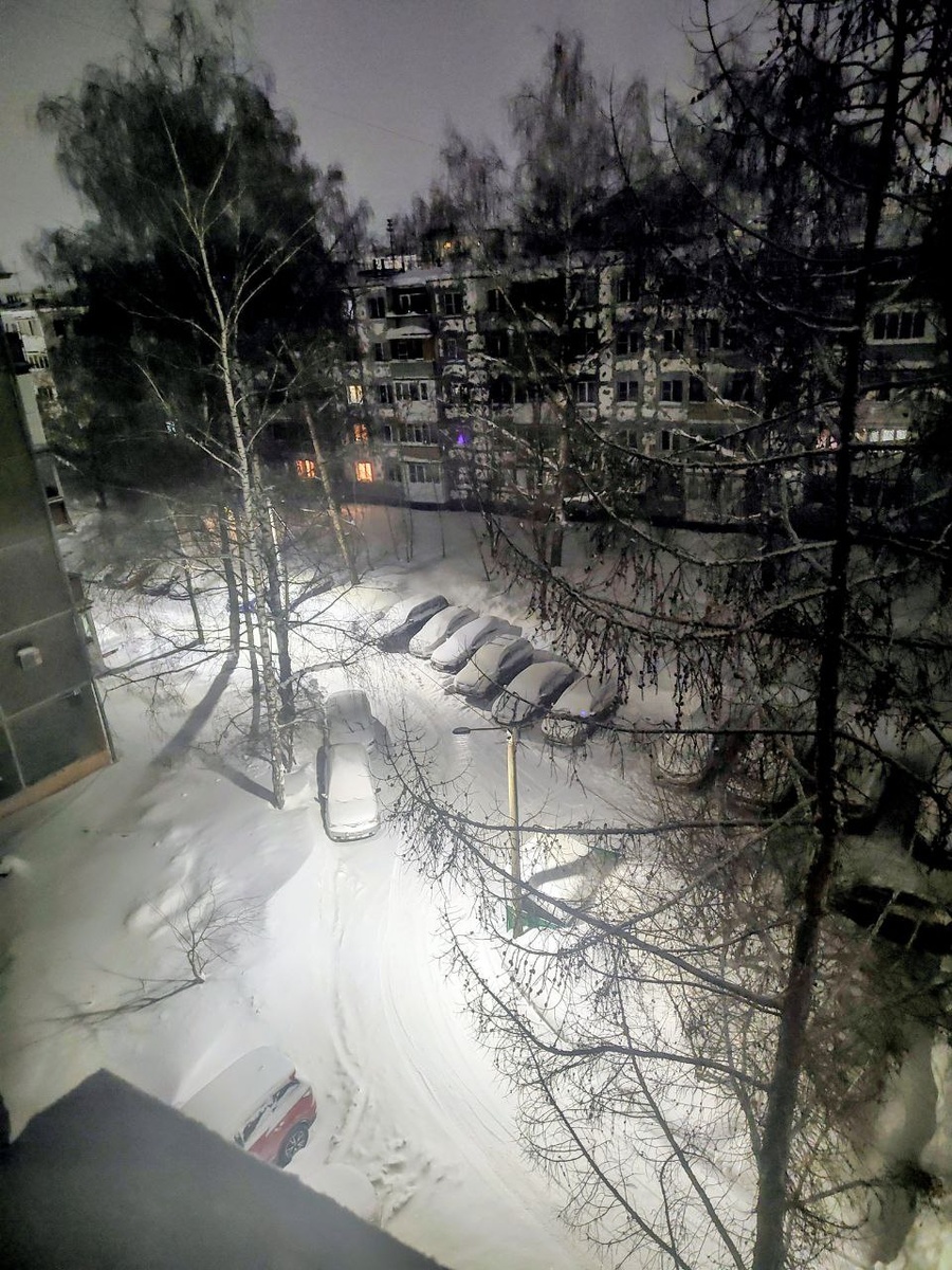 Фото автора из окна. Время 5.30 утра 02.02. На пустующем месте в ряду заснеженных машин стояла наша. Но теперь муж на ней уже на работу уехал...А снег всё идёт - это в свете фонаря видно