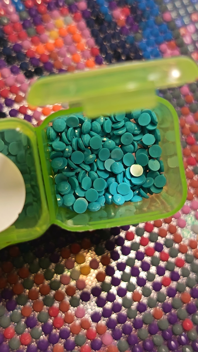 Откройте бокс. Аккуратно приподнимите крышку, не переворачивая контейнер. Выберите стразу. Если стразы уложены слоями, слегка потрясите бокс, чтобы нужный элемент оказался сверху.