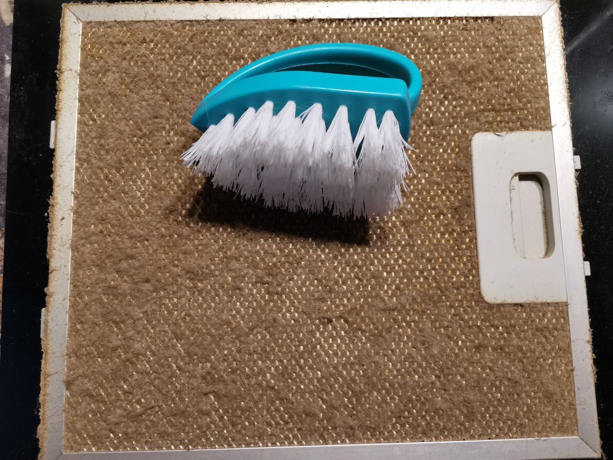 Снимаем фильтр с вытяжки и берём жёсткую щётку