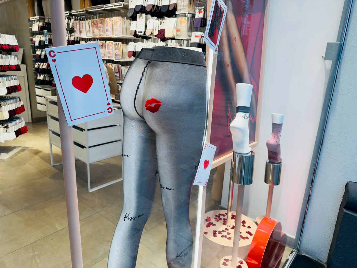 Эта витрина — не про любовь и не про иронию, а про откровенное обесценивание. Женщина здесь сведена к фрагменту тела, а отношения — к дешевому визуальному жесту, который эксплуатирует сексуальность вместо смысла. День святого Валентина в такой подаче превращается не в разговор о близости, выборе и взаимности, а в банальную витрину потребления, где чувства заменены принтом, а достоинство — шуткой ниже пояса. Это не провокация и не смелость, а усталый язык индустрии, которая так и не научилась говорить о любви иначе, чем через унижение и редукцию. Фото: Хатуна Колбая