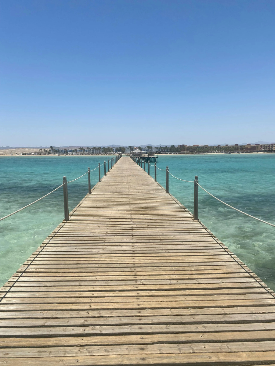 Деревянный пирс протянулся над прозрачными бирюзовыми водами Красного моря на египетском курорте