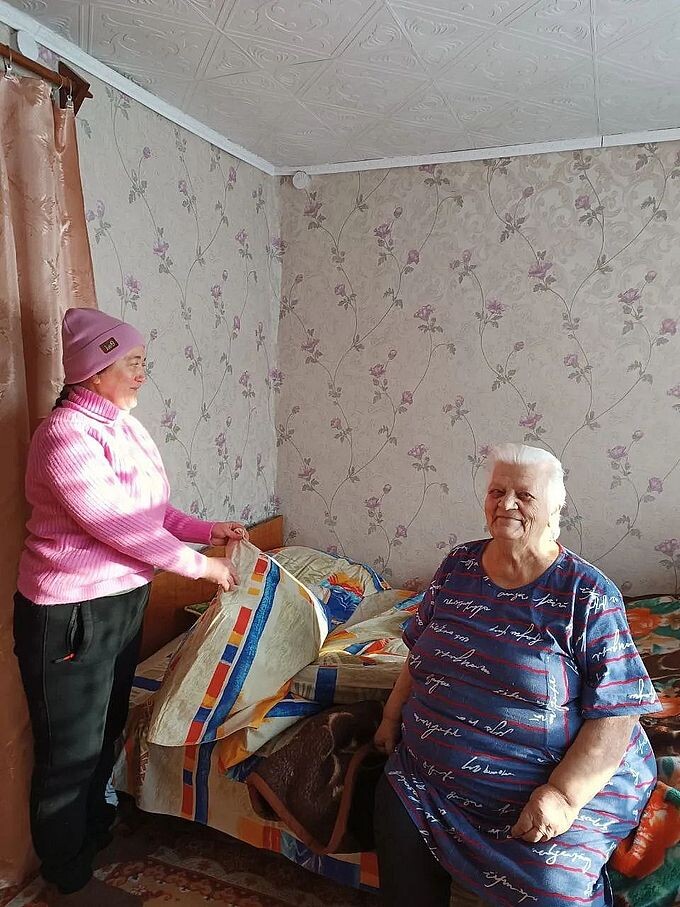 Социальный работник заправляет постель