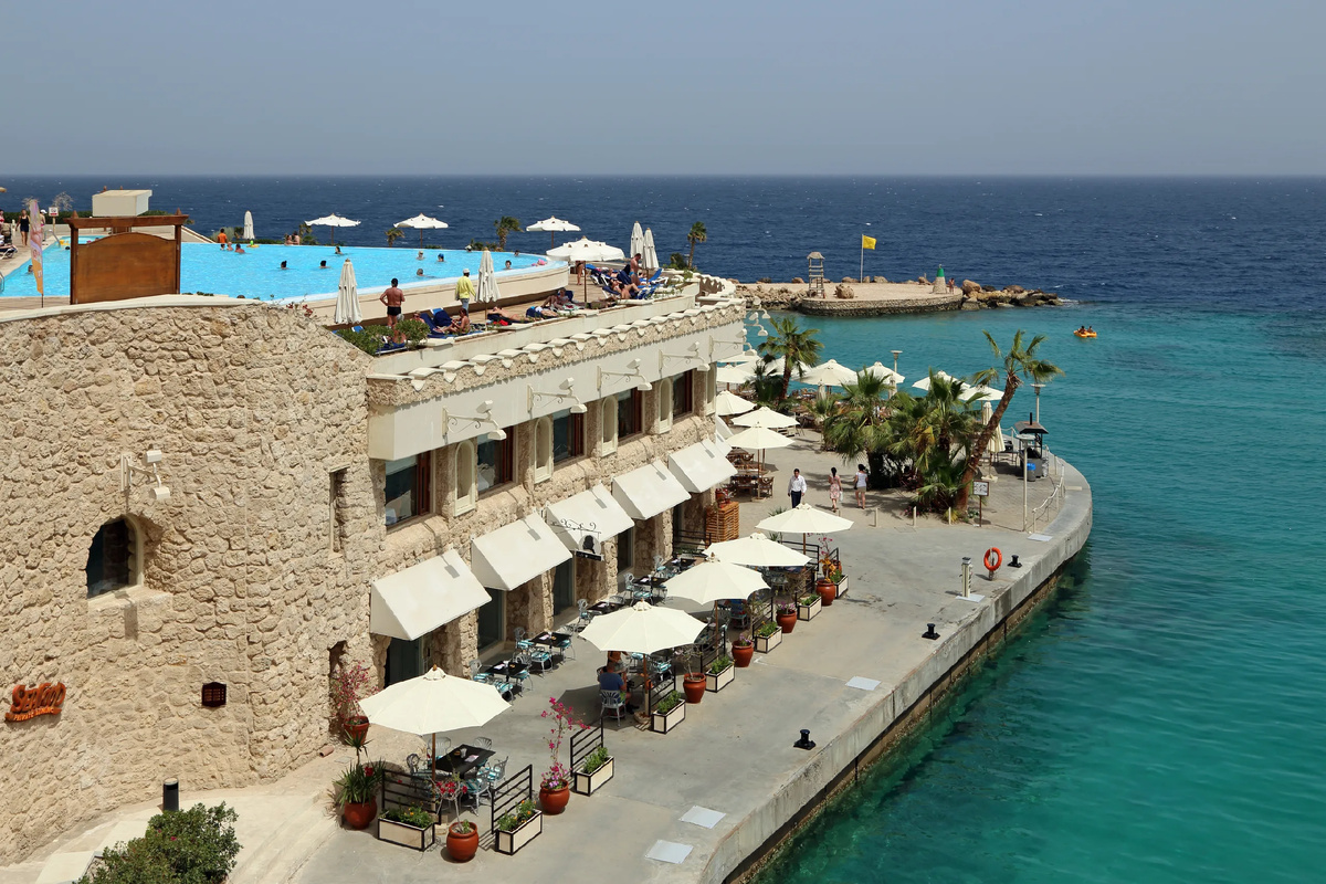 Роскошный турецкий курорт с голубым бассейном, шезлонгами и видом на Средиземное море весной