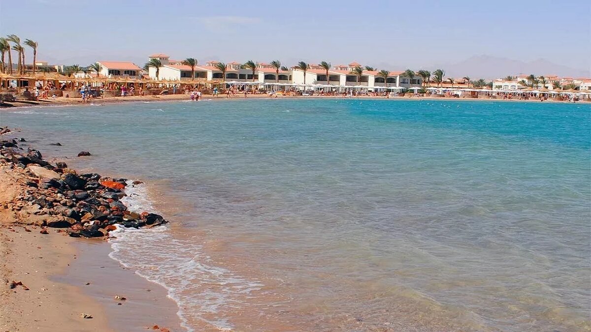 Пляж Шарм-эль-Шейха с бирюзовым Красным морем, белым песком и рядами шезлонгов под пальмами в марте