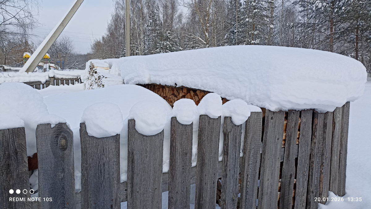 Снег создал узор на заборе. Лег толстым слоем на дрова. Фото автора.