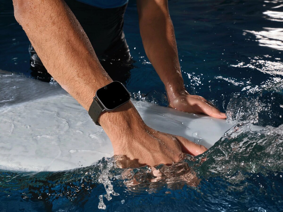 Изящные и современные Xiaomi Redmi Watch 5 Active, которые выделяются на переднем плане своим темно-черным цветом и минималистичным дизайном. Круглый циферблат часов оснащен ярким дисплеем, отображающим различные интеллектуальные функции, такие как отслеживание физической формы и уведомления. Центральное место в стильной обстановке с мягким фокусом занимает письменный стол с техническими гаджетами, тонко намекающий на стиль жизни, основанный на функциональности и инновациях. На заднем плане часы украшены мягким градиентом, придающим им ощущение глубины, а теплое естественное освещение создает приятную атмосферу. Композиция должна быть снята под небольшим углом, чтобы подчеркнуть особенности часов и сохранить четкий и профессиональный вид, подходящий для обзора продукта. Не должно быть никакого текста, логотипов или водяных знаков.