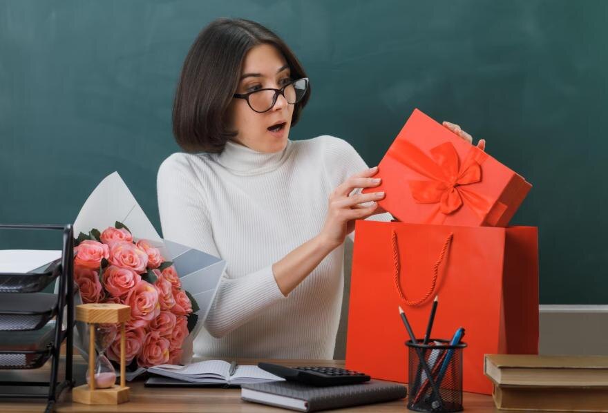https://ru.freepik.com/free-photo/surprised-young-female-teacher-holding-looking-present-sitting-desk-with-school-tools-classroom_26884848.htm