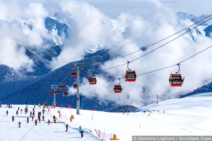 Архыз, Россия — 23 января 2024 года: Туристы катаются на лыжах и сноубордах на горнолыжном курорте «Архыз». Канатная дорога на курорте Архыз на фоне гор в солнечный зимний день