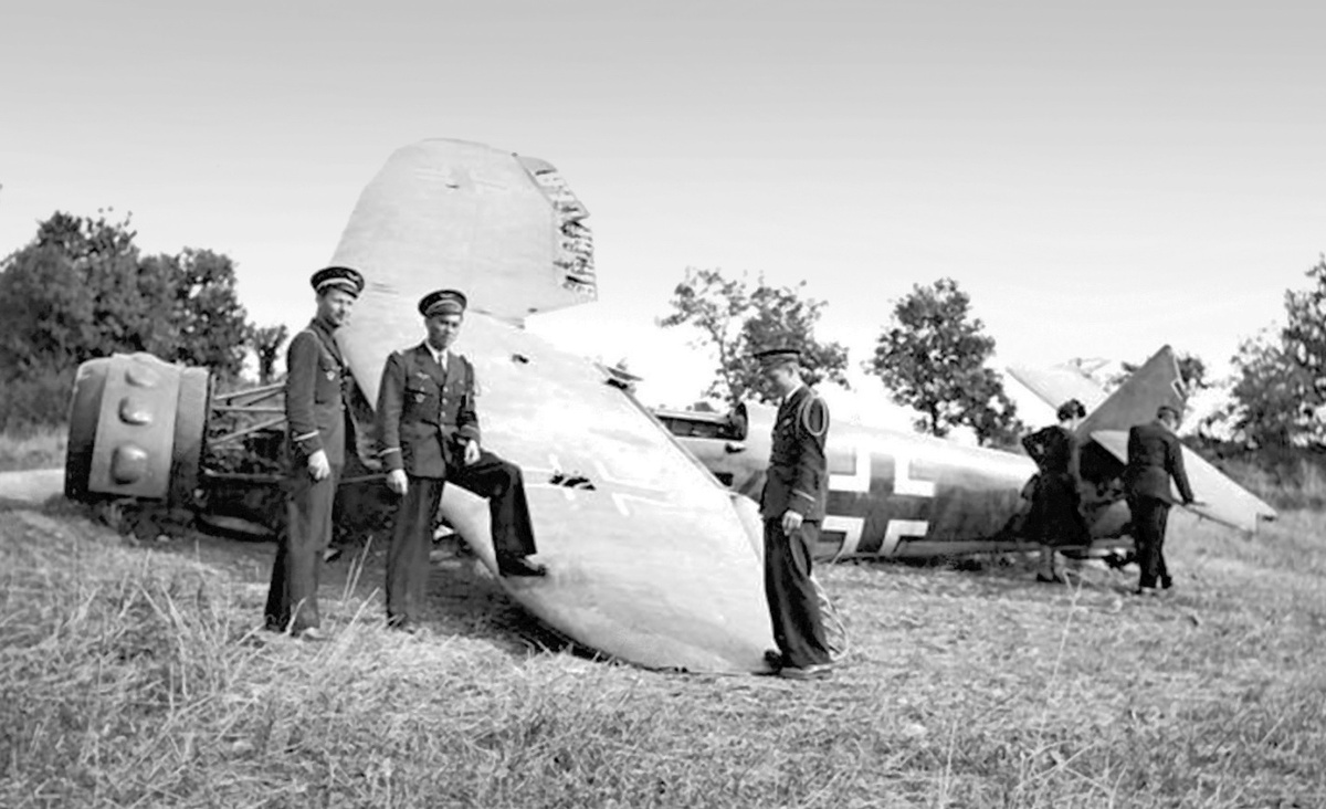 Французские летчики капитан Сарро, су-лейтенант Маршелидон и су-лейтенант Пенс из авиагруппы GC I/2 фотографируются возле сбитого в бою 24 июня германского самолета "Хеншель" Hs-126 из 5-го штаффеля 13-й разведывательной группы. Франция, департамент Дром, район Роман-сюр-Изер, конец июня 1940 года.