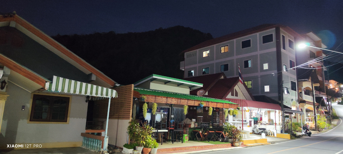 Вид на дом вечером, за ним гора.