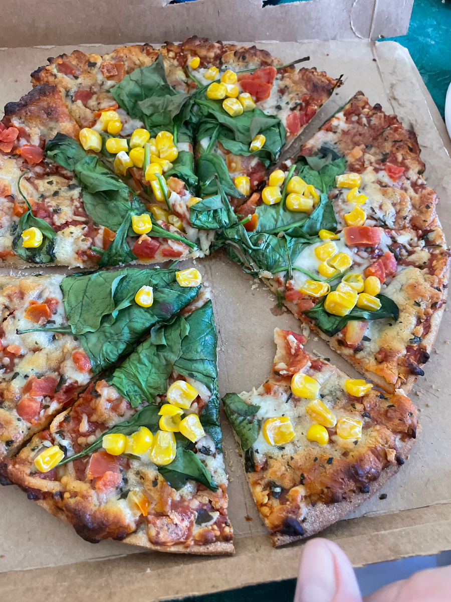 Кусочек пиццы глютен-фри из цветной капусты. Поверх набросала шпинат и кукурузу