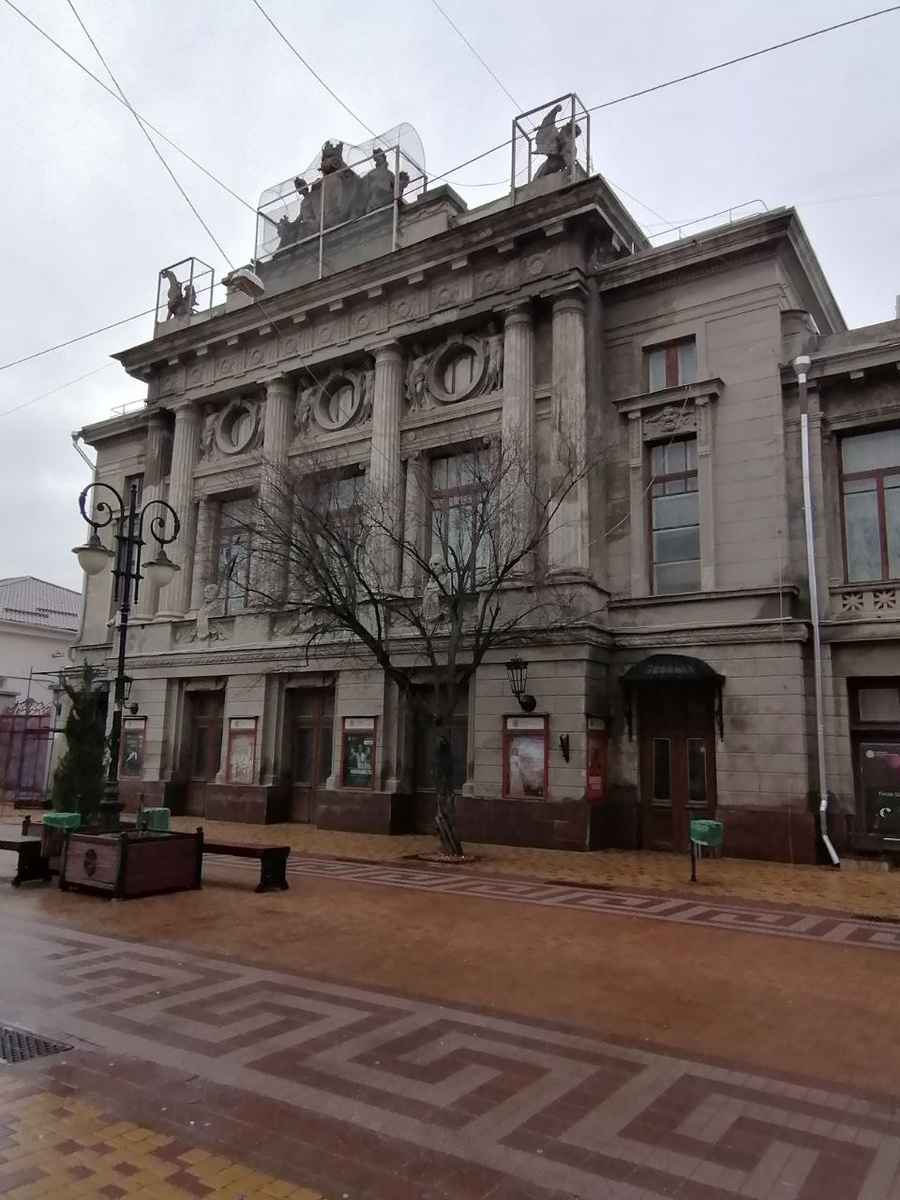 Театр в 2026 году. Фасад практически не изменился, только скульптуры грифонов, Аполлона и Мельпомены огорожены сеткой. 