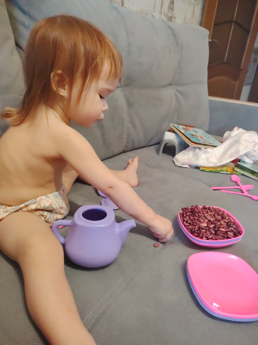 Принесла фасоль из своей комнаты, залезла на диван и играет
