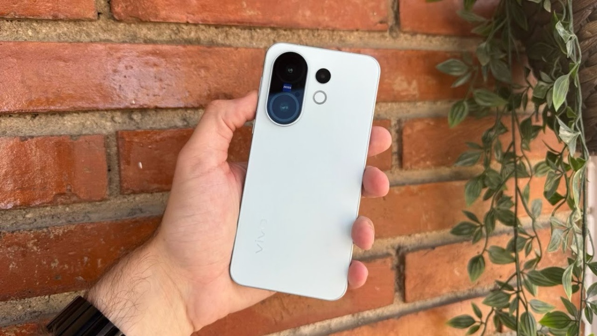 Крупный план смартфона vivo X200 FE, демонстрирующий его элегантный дизайн в элитном черном цвете. На переднем плане заметно выделяется 6,3-дюймовый AMOLED-дисплей с яркими цветами и четкой графикой. Смартфон расположен под небольшим углом, что подчеркивает его тонкий профиль и высококачественную отделку с едва заметными отблесками на поверхности. На заднем плане слегка размытая офисная обстановка намекает на высокотехнологичную обстановку, освещенную мягким естественным светом, который создает теплое свечение, подчеркивающее утонченную эстетику устройства. Композиция отражает ощущение современной элегантности, идеально подходящей для технического обзора, с акцентом на дизайн телефона и передовые функции, вызывая восхищение и интригу, не отвлекаясь ни на что другое.