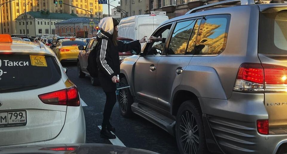    Девушка получает деньги от водителя за мытье фар его автомобиля, пока он стоял в пробке в Москве / РИА «Новости»