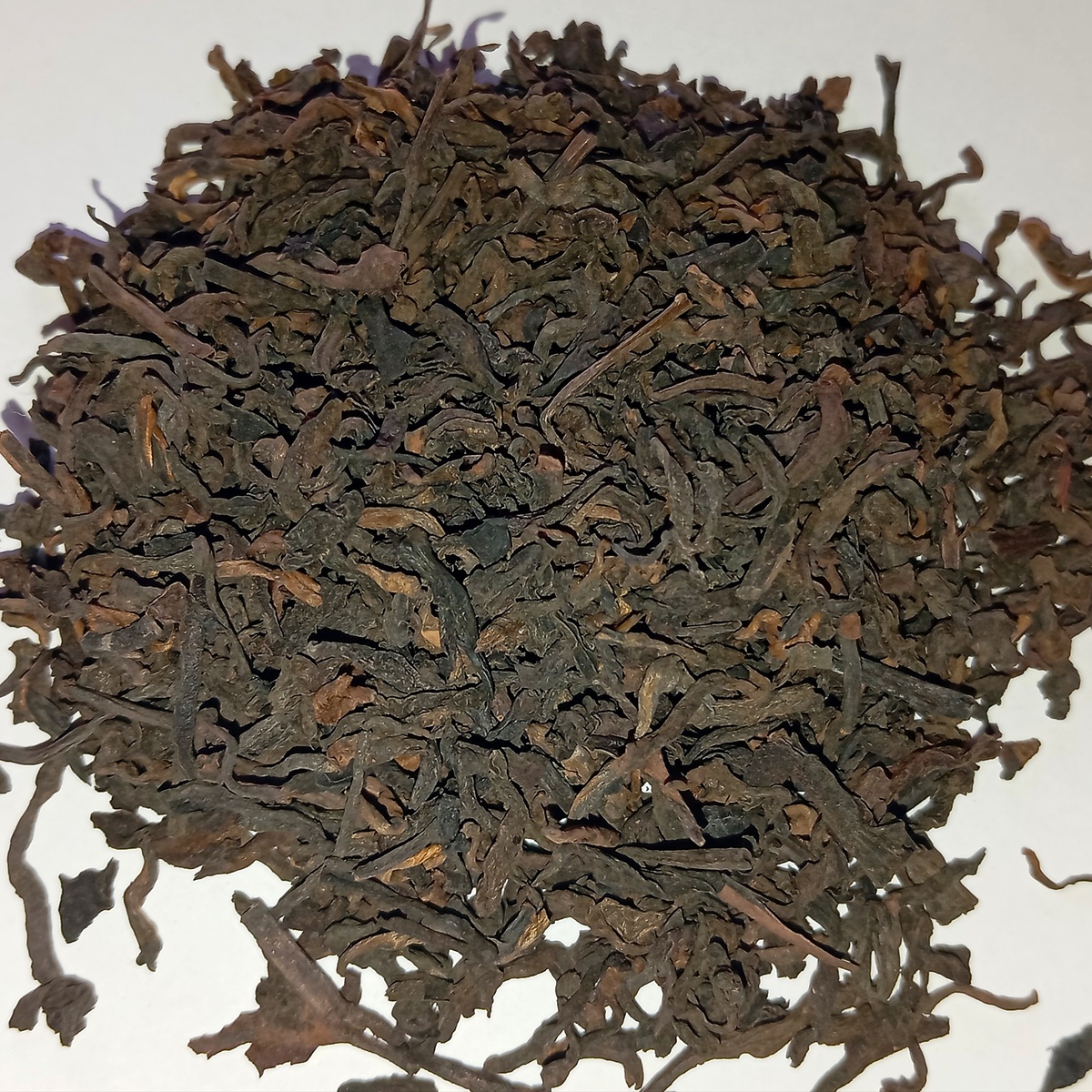 Фото автора. Как выглядит сухой чайный лист шу пуэра на белом листе бумаги 