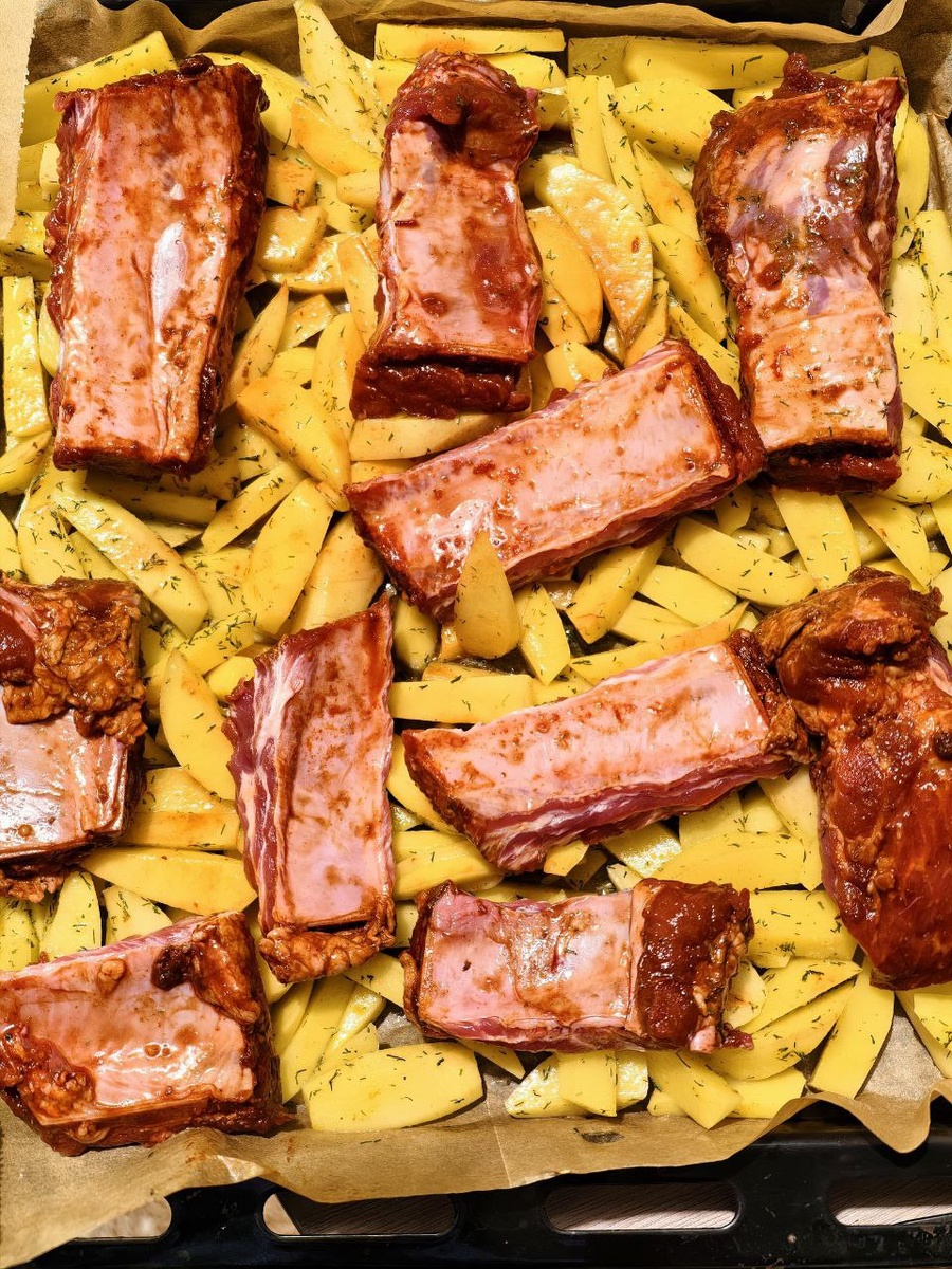 Шаг 2, 5 минут. Ребрышки кладу поверх картошки. Всё сбрызгиваю маслом, посыпаю солью, перцем, паприкой — что есть. Маринад? Его роль сейчас играет время и жар духовки