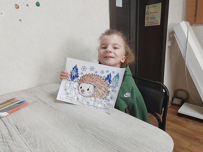 Девочка показывает созданную ею аппликацию