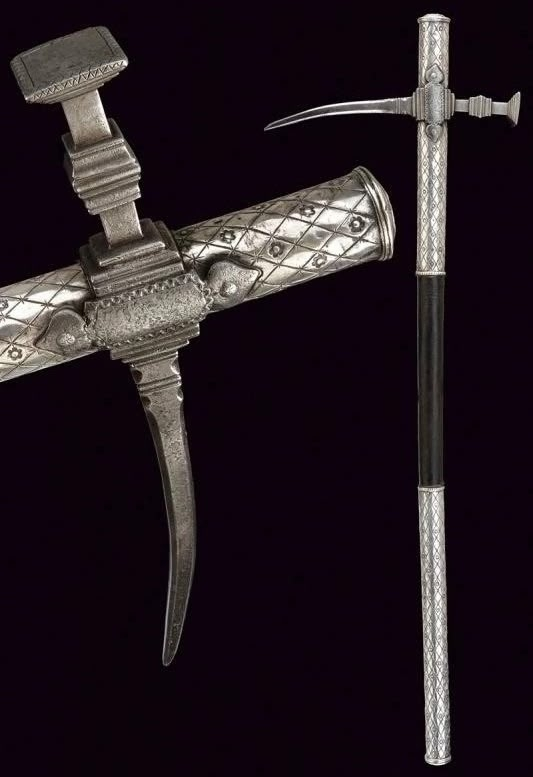 Клевец, Восточная Европа (скорее всего Польша), датируется примерно 1700 годом. Длина оружия 800 мм. Боевая часть оружия состоит из узкого граненого "клюва" с декоративно оформленной "шейкой" и молотообразного бойка на обушной части, с узким основанием и расширенной плоской ударной площадкой. Рукоять деревянная, снизу и сверху обложена металлическими листами с серебрением и декором.