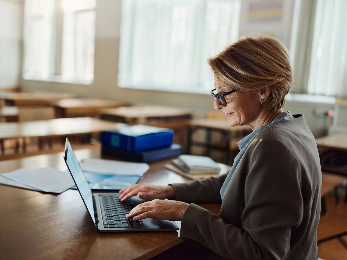    Учительница работает за ноутбуком в школе | © iStock.com / skynesher