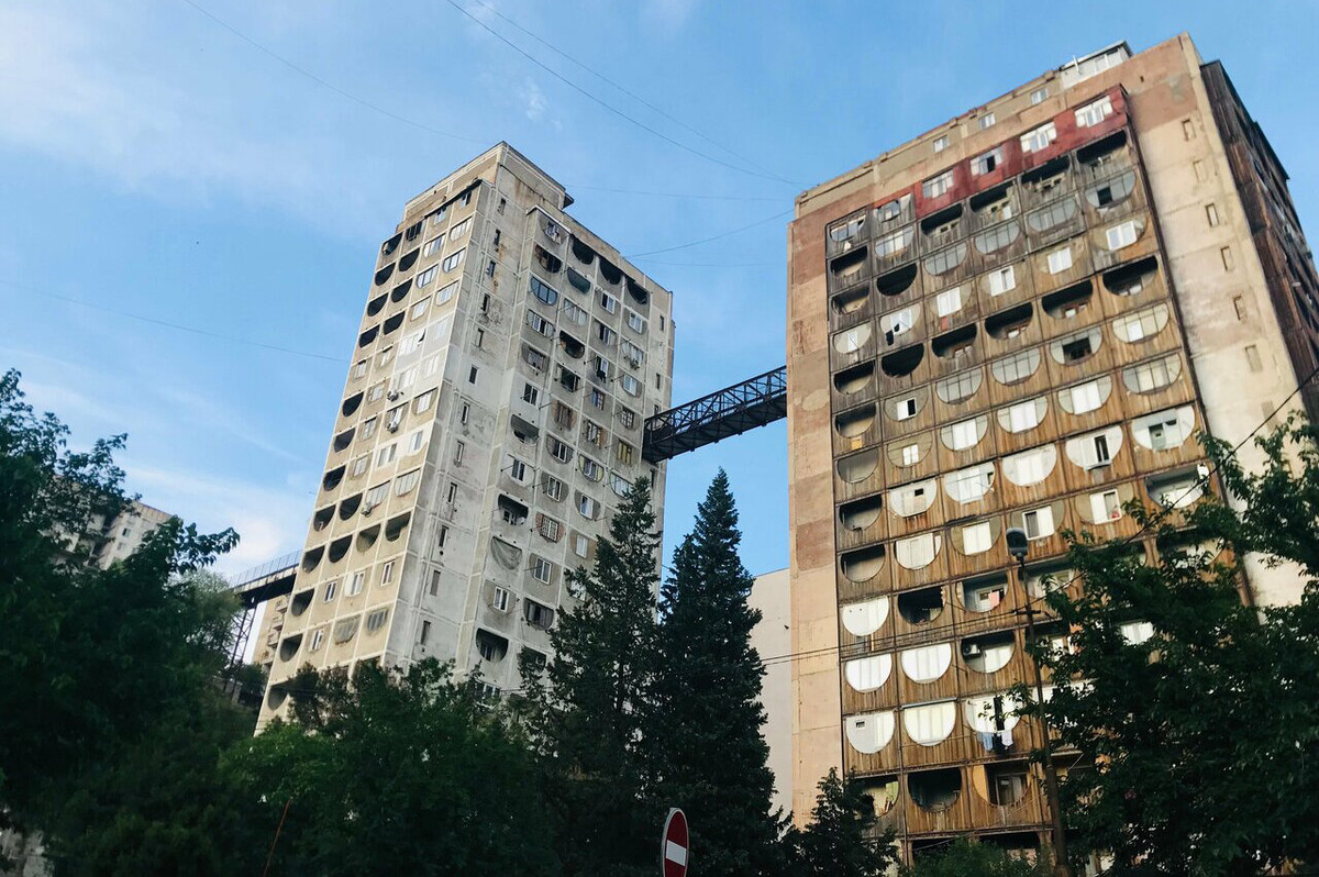 Изюминка многоэтажек в том, что попасть внутрь можно не только с первого этажа, но и по мосту, расположенному между 12-м и 15-м этажами. Это сделали для удобства местных жителей: дома стоят на склоне холма с крутым подъёмом, поэтому иногда попасть сюда проще сверху, чем снизу. Фото: Семён Орлов / Яндекс Карты