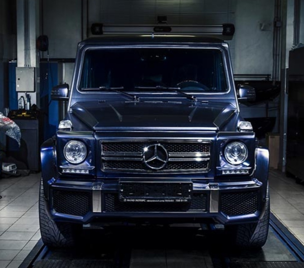 Mercedes-Benz G-Class, известный как «Гелик» или «Гелендваген» (от нем. Geländewagen — внедорожник), — это культовый немецкий автомобиль, выпускающийся с 1979 года. Изначально созданный как военный транспорт, он эволюционировал в символ успеха, сочетая брутальный угловатый дизайн, высокую проходимость (клиренс до 220 мм) и премиальную роскошь. Модель славится ручной сборкой, рамой, неразрезными мостами и сохранением классического облика на протяжении десятилетий. Ключевые особенности и факты:История: Разработан в 1970-х, серийное производство началось в 1979 году. Первая серьезная смена поколения произошла только в 2018 году, сохранив при этом узнаваемые черты. 