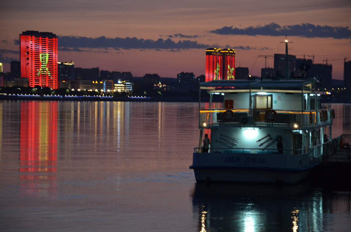 Река Амур — место встречи загадочного Востока и прагматичного Запада на расстоянии меньше километра. Теплоходик стоит у российского берега, а небоскрёбы светятся уже на китайском.