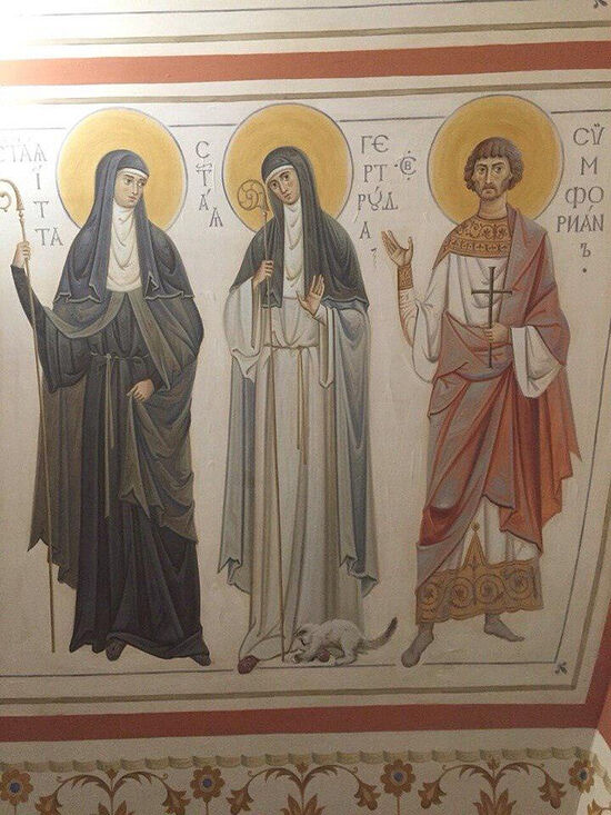 Гертруда Нивельская (626 год — 17 марта 659 года) — святая, почитается как в католичестве, так и в православии. Что интересно, изначально изображалась с посохом и мышью. Но в 1980-х мышь сочли животным недостойным (грязь, чума и все такое) и стали изображать с кошкой. Тогда же появилось объяснение этой метаморфозы  —  при монастырях жило много кошек, для защиты припасов и книг от грызунов, а святая была настоятельницей.