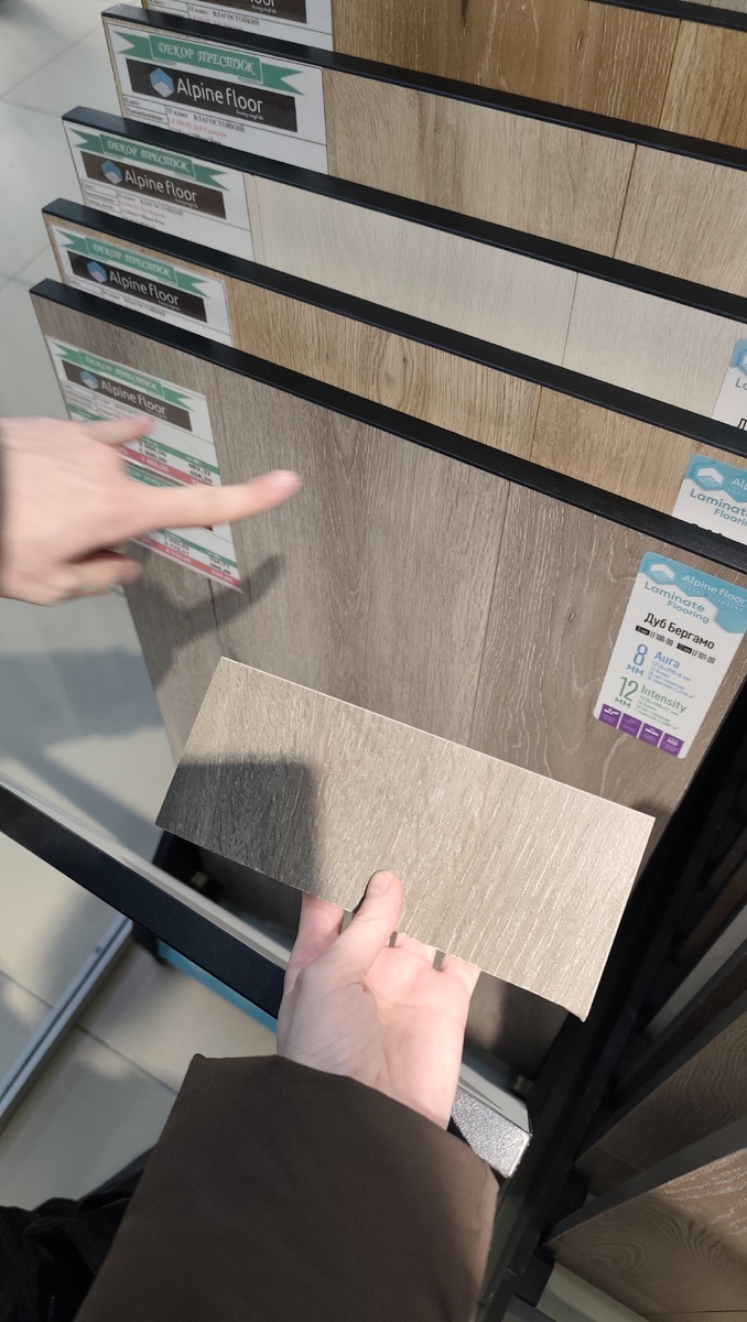 У меня в руке кусок нашей плитки, на заднем плане ламинат. 