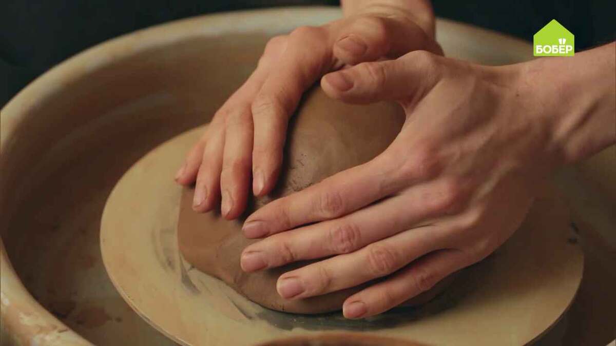 Торцом ведущей руки плотно примажьте глину к гончарному кругу.