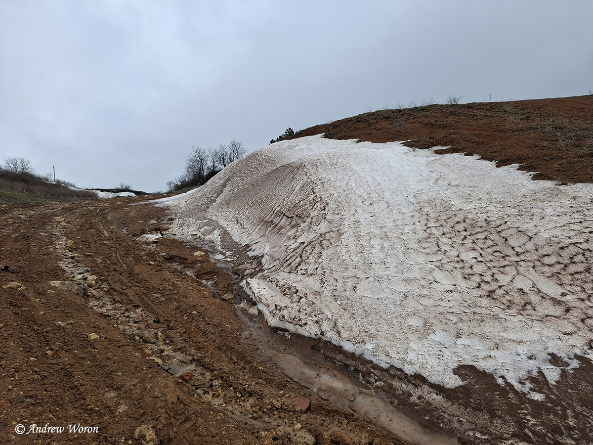 Снежник на краю дороги, ведущей к берегу