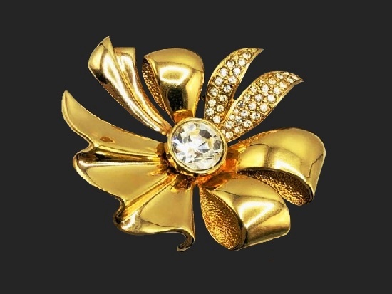 Брошь в виде банта. Полированный и текстурированный металлический сплав золотистого цвета, инкрустированный стразами. 1980-е годы.