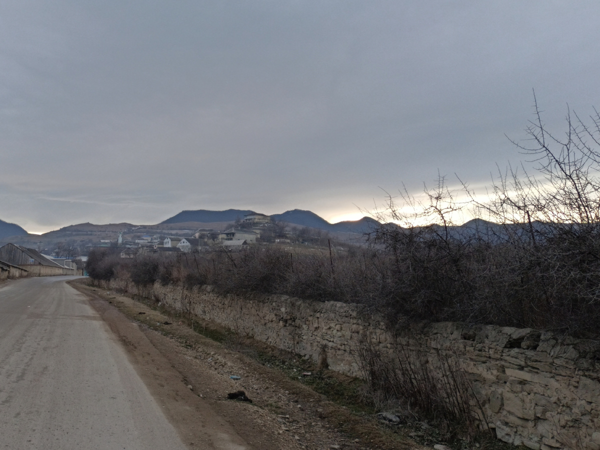 Фото автора: справа от дороги, за каменной кладкой и колючими кустами – старое сельское кладбище (Дагестан, январь 2024)