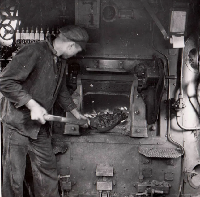 Кочегар паровоза, бросает уголь в топку.