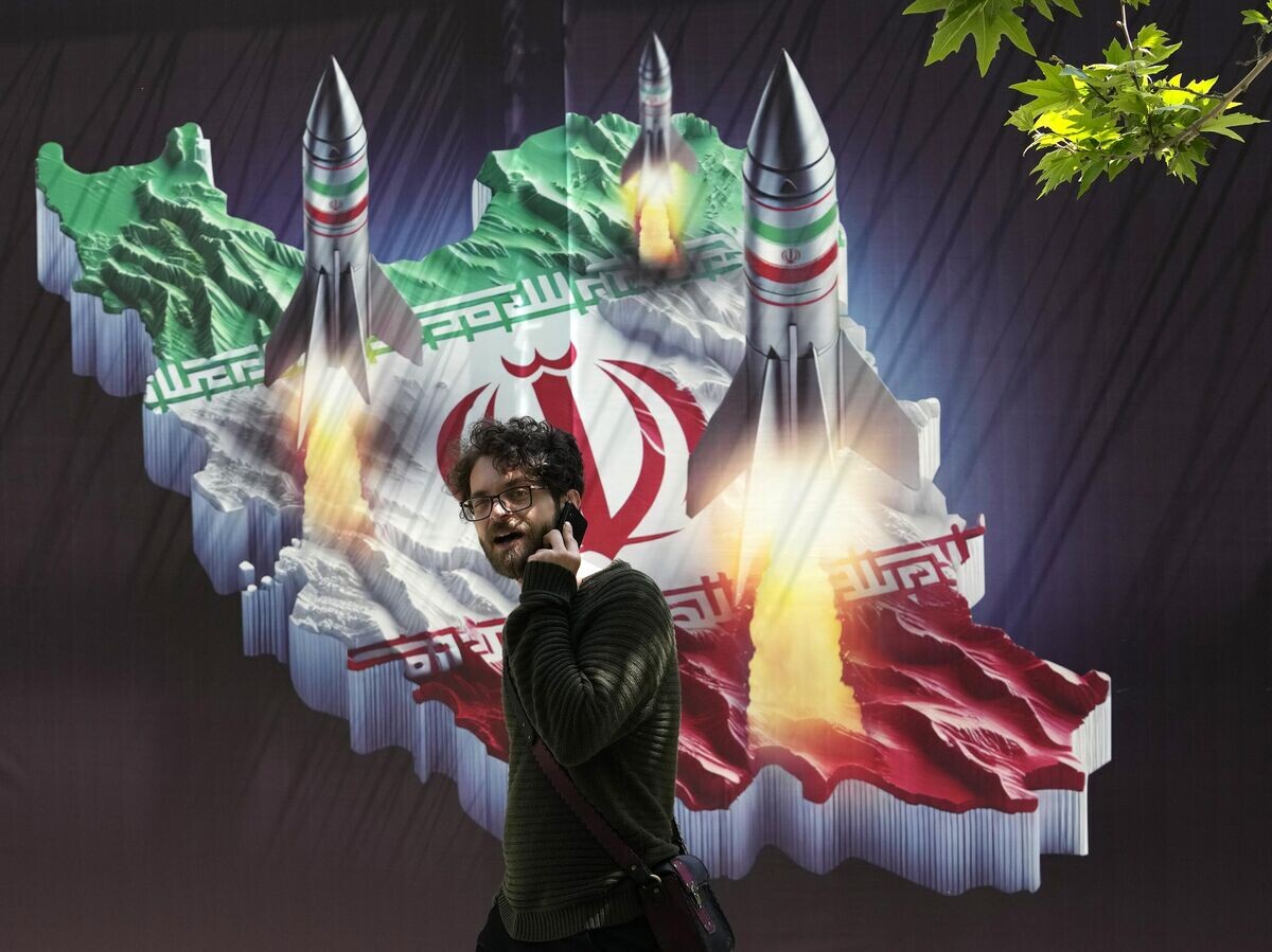    Мужчина проходит мимо баннера, на котором изображен запуск ракет с карты Ирана, в Тегеране | © AP Photo / Vahid Salemi