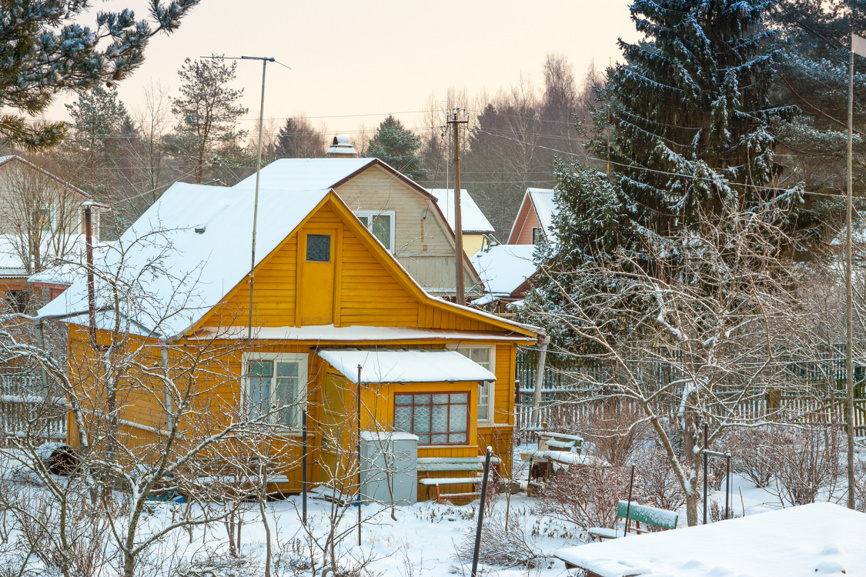 Старый дачный домик зимой на заснеженном участке, вид рельефа без растительности