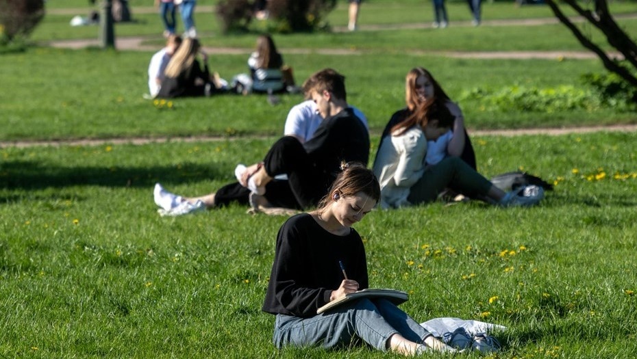    Девушка работает с ручкой и тетрадью на коленях сидя на траве газона Марсова поля. Автор фото: Тихонов Михаил