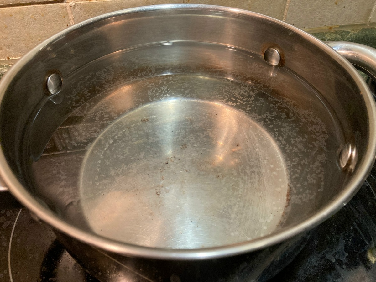 Скопления кристалликов накипи плавают на поверхности воды после кипячения.