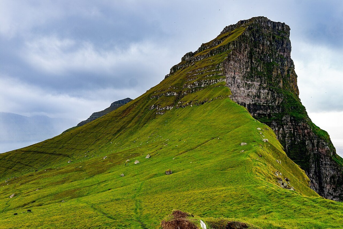 Известные на весь мир террасообразные склоны Фарер сформировали потоки базальтовой лавы, а ледниковая и морская эрозии образовали крутые утёсы, расщелины и фьорды. Фото: Sanshiro KUBOTA / Wikimedia