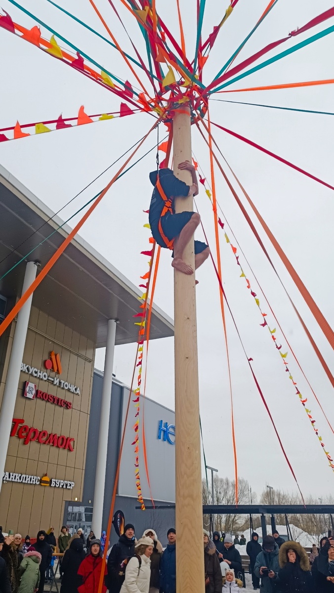 Старинная русская забава. Пока я ела обязательный блин и пила очень вкусный сбитень, на столб залезли несколько отважных голоногих мужчин. Этот на фото получил наушники для смартфона (не сапоги). 