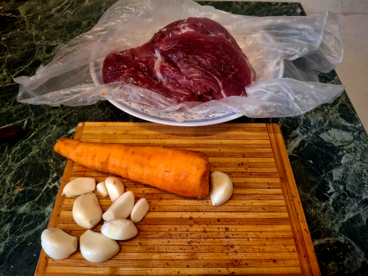 Фотография сделана автором статьиКусок потолще свинины надо нашпиговать морковью и чесноком. Это не трудно. Делаешь острым ножом прокол и вставляешь по лезвию палочку моркови или зубчик чеснока. На фотографии начало работы, поэтому  пока мало проколов  с чесноком и морковкой.