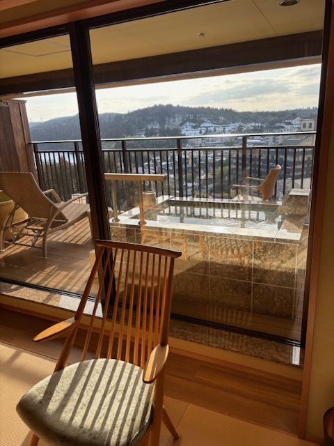 Горячий источник на балконе рёкана, в темное время суток видно как от воды поднимается пар